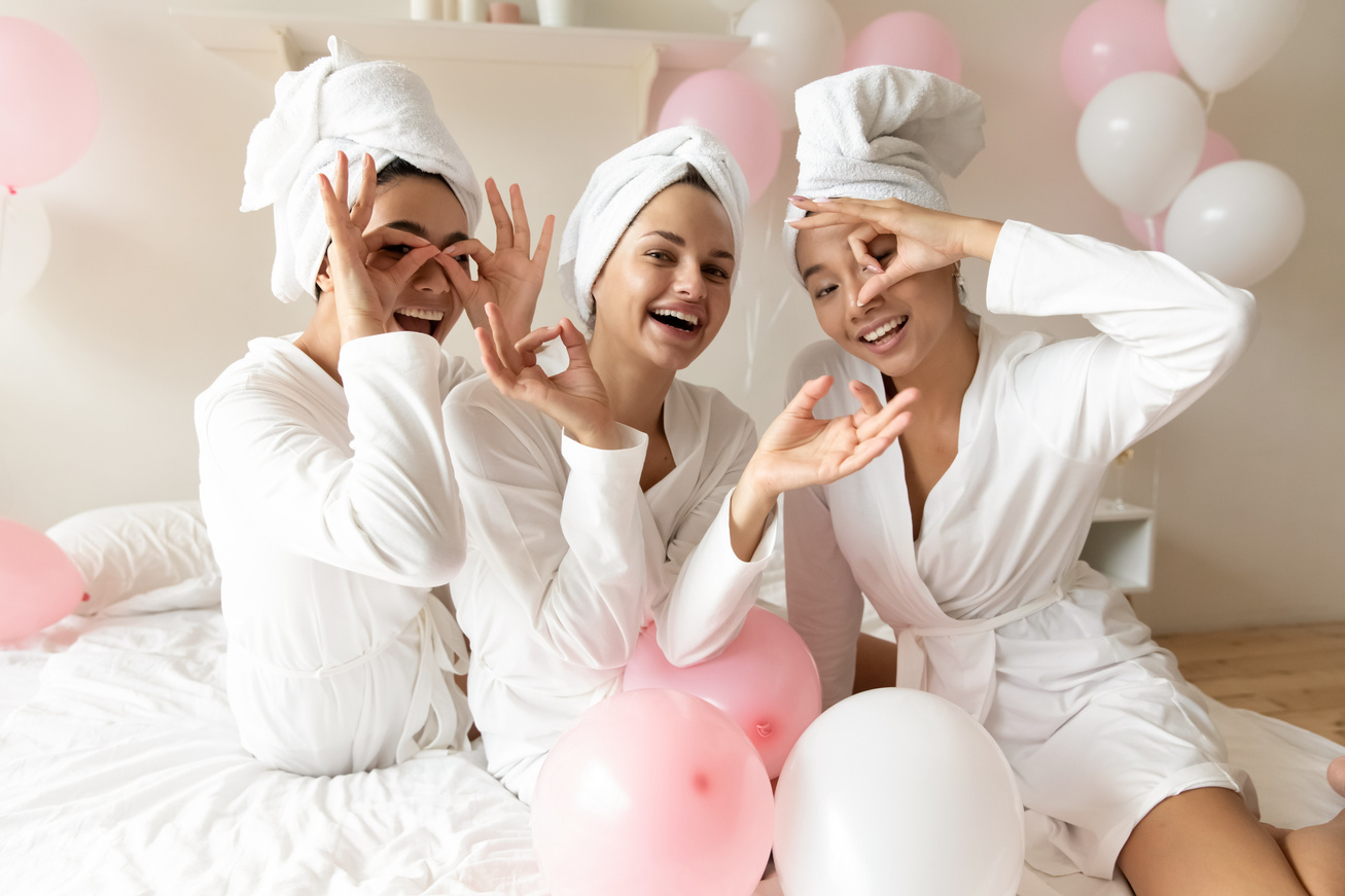 Women in bathrobes making binoculars with fingers celebrating bachelorette party